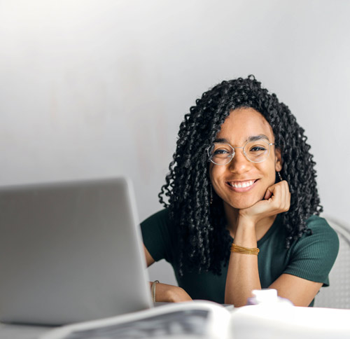 young woman smiling at laptop with curly hair