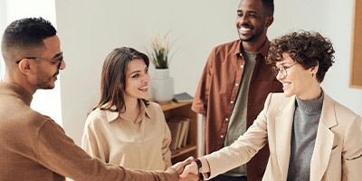 four individuals engaged in a handshake discussing business opportunities