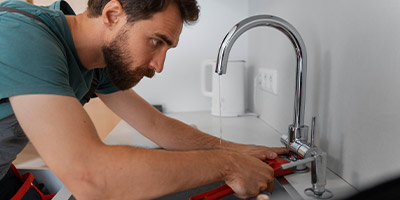 man using a wrench on a kitchen faucet