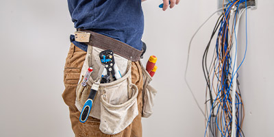 person wearing tool belt with various tools and wires